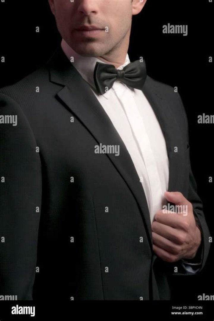 A man in a black suit and a red tie smiling.