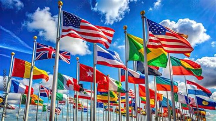 Flags from numerous countries wave in the wind on flag posts.